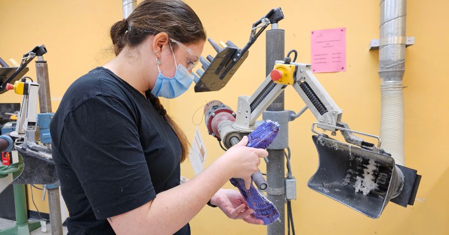 Une technicienne sable une orthèse pour l’ajuster à la morphologie d’un jeune usager