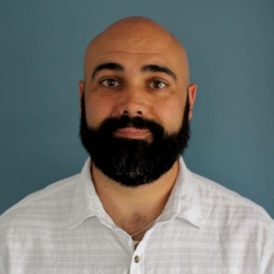 Franck Boulasladj, infirmier Un homme sans cheveux et portant une barbe noire et une chemise blanche.