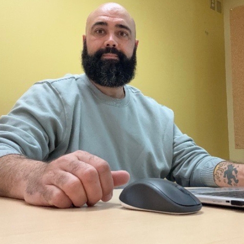 CIUSSS-Estrie-LGBTQ Un homme à barbe noire devant un ordinateur.
