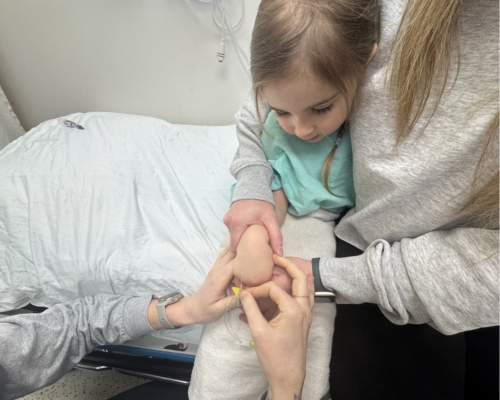 Le réconfort d’un parent peut faciliter les soins. Une enfant en jaquette d'hôpital collée sur sa maman.