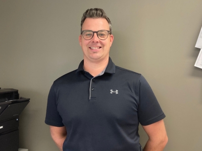 Un homme souriant portant un chandail noir.<br />
