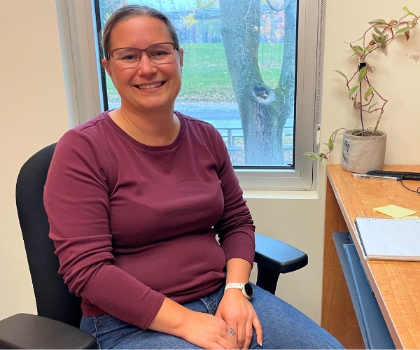 Une femme assise avec un chandail mauve.