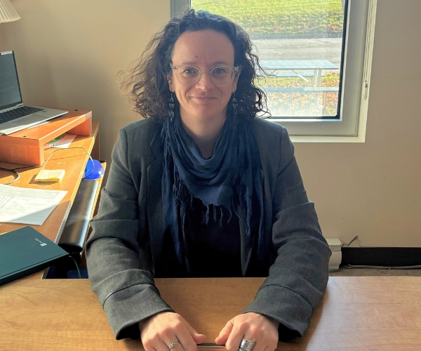 Une femme aux cheveux bruns attablée à son bureau. 