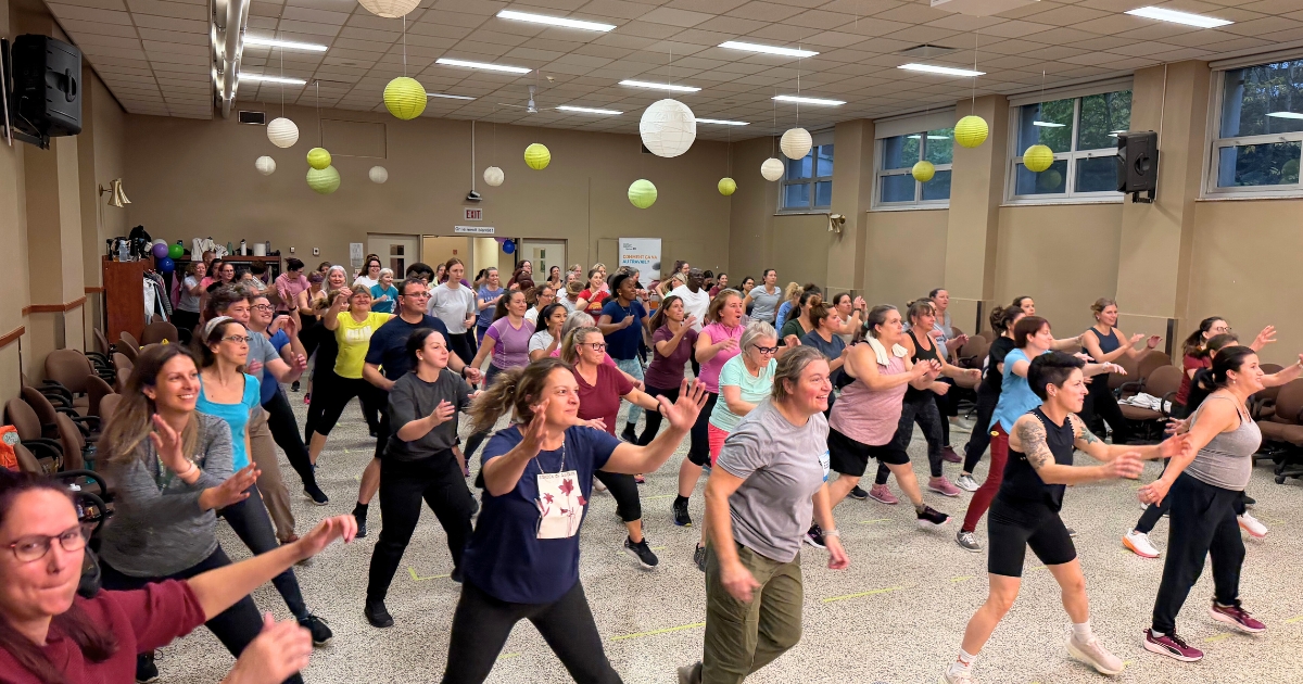 Un groupe de 100 personnes qui dansent dans un gymnase.