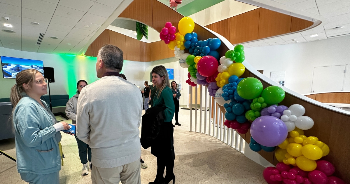 Dans l'atrium, des gens parlent entre eux autour de ballons colorés.