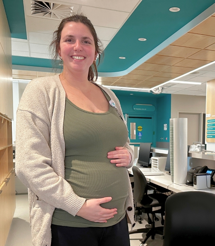Une employée enceinte pose fièrement, car elle sera bientôt une usagère utilisant le nouveau pavillon de naissance. 