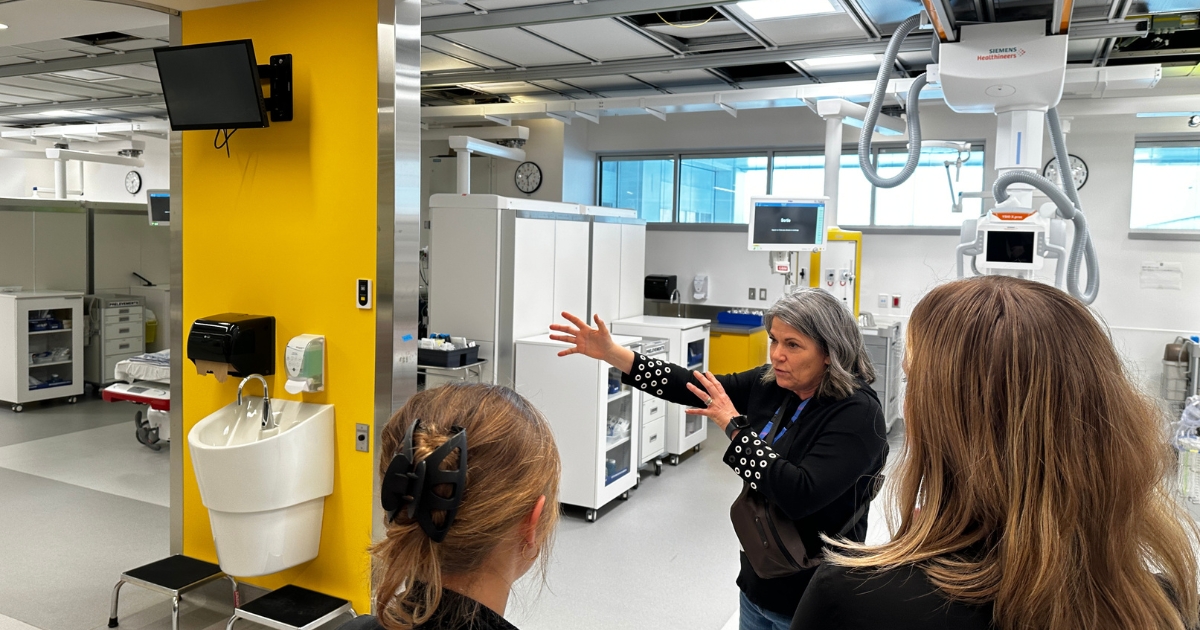 Une femme aux cheveux blancs présente les locaux jaune à un groupe. 