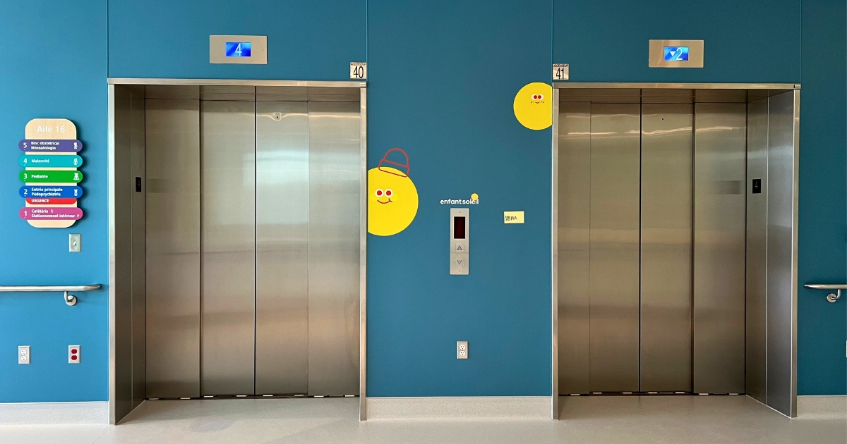 Deux portes d'ascenseur avec signalisation colorée à gauche.