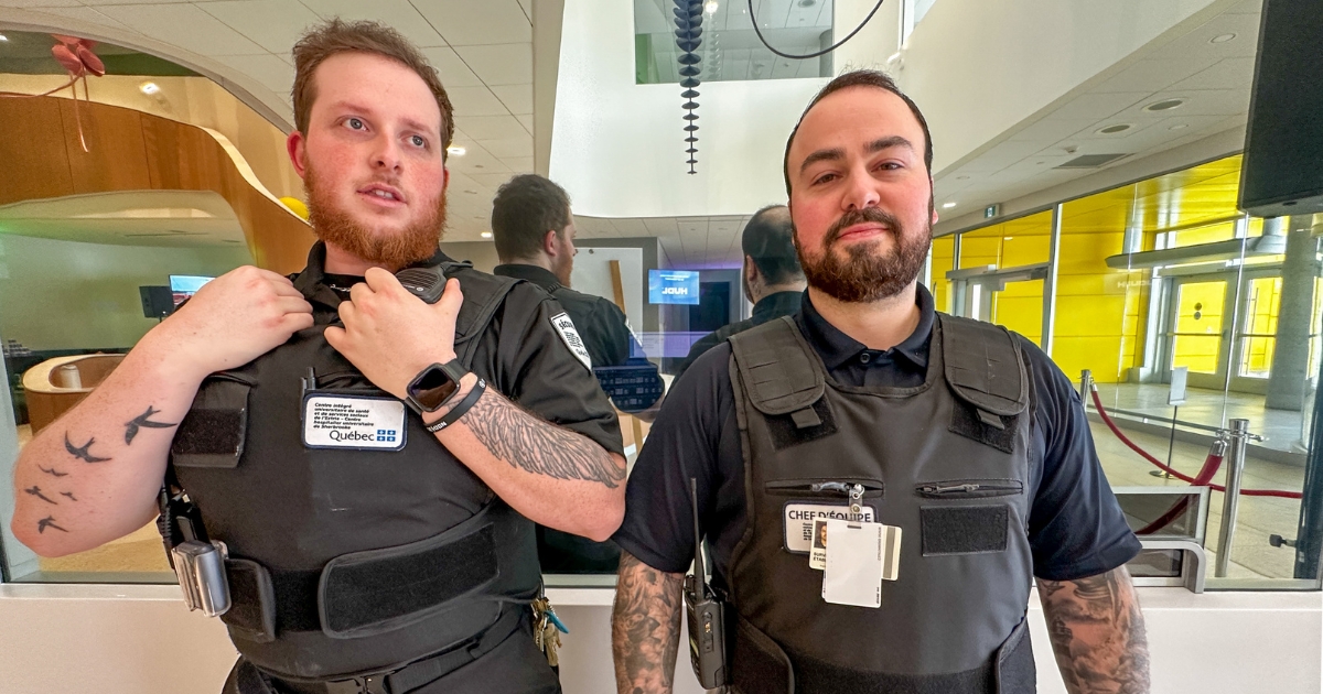 Deux agents de sécurité en action devant une vitre miroir. 