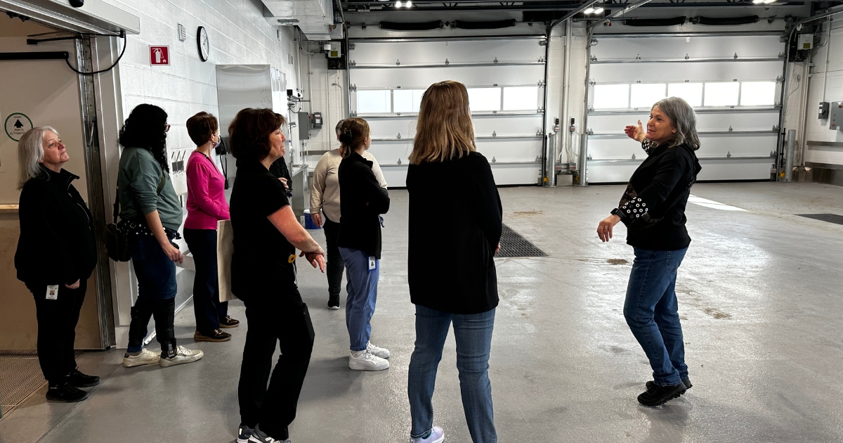Un groupe de visiteurs dans un garage immaculé blanc pour recevoir bientôt les ambulances.