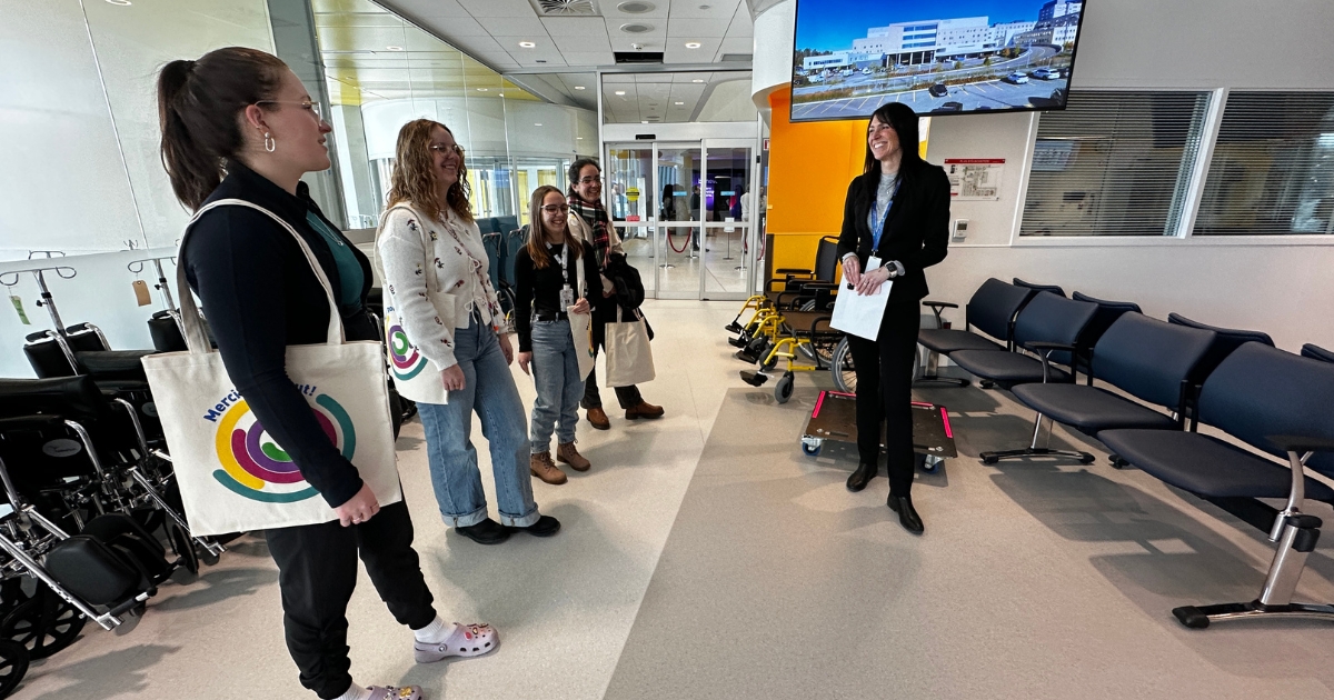 Une femme aux cheveux bruns fait visiter une salle d'attente vide. 