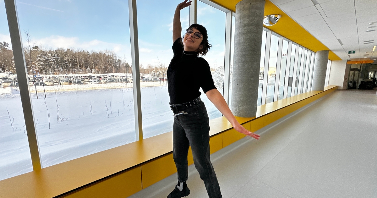 Une jeune femme saute de joie dans un corridor éclairé. 