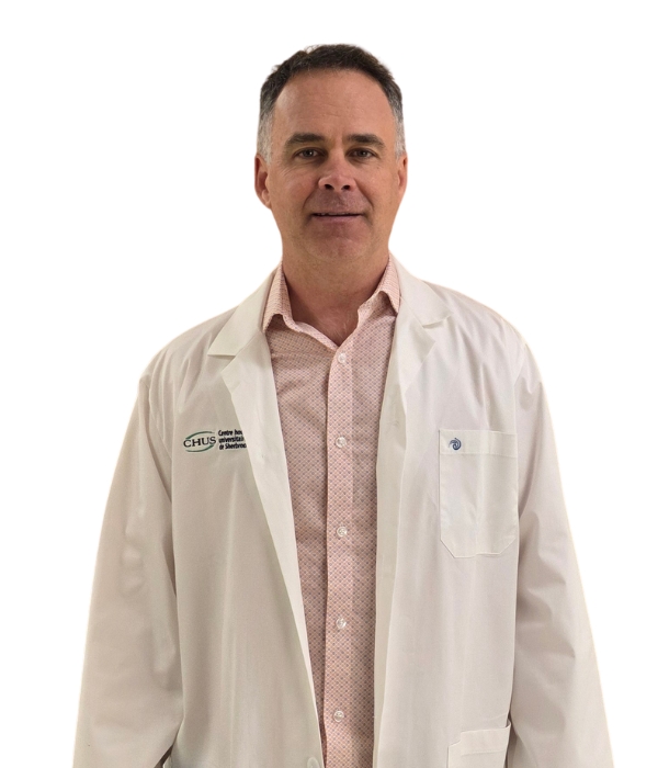 Un homme en sarrau qui regarde la caméra.