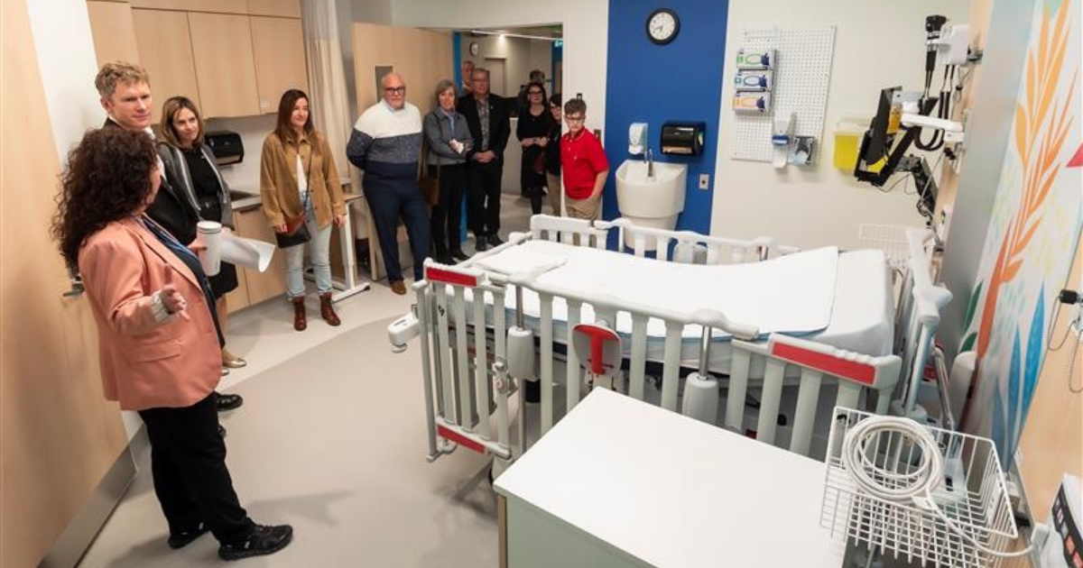Une femme fait visiter à un groupe une chambre d'hôpital au goût du jour.