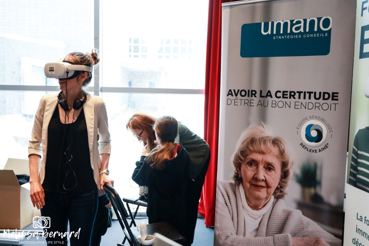 Au kiosque Umano, une visiteuse fait l'expérience du casque de réalité virtuel de la formation EDIE, pour découvrir la maladie d’Alzheimer du point du vue d’une personne qui en est atteinte.