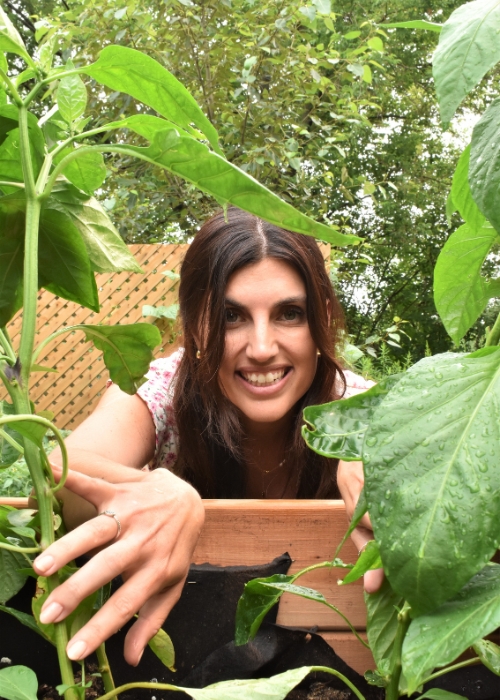 Une femme aux cheveux bruns parmi la verdure.